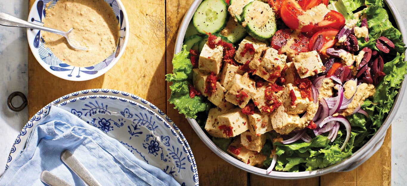 Η ελληνική σαλάτα με φέτα Tofu που έχει αποξηρανθεί από τον ήλιο σε ένα λευκό μπολ σε ένα ξύλινο επιτραπέζιο