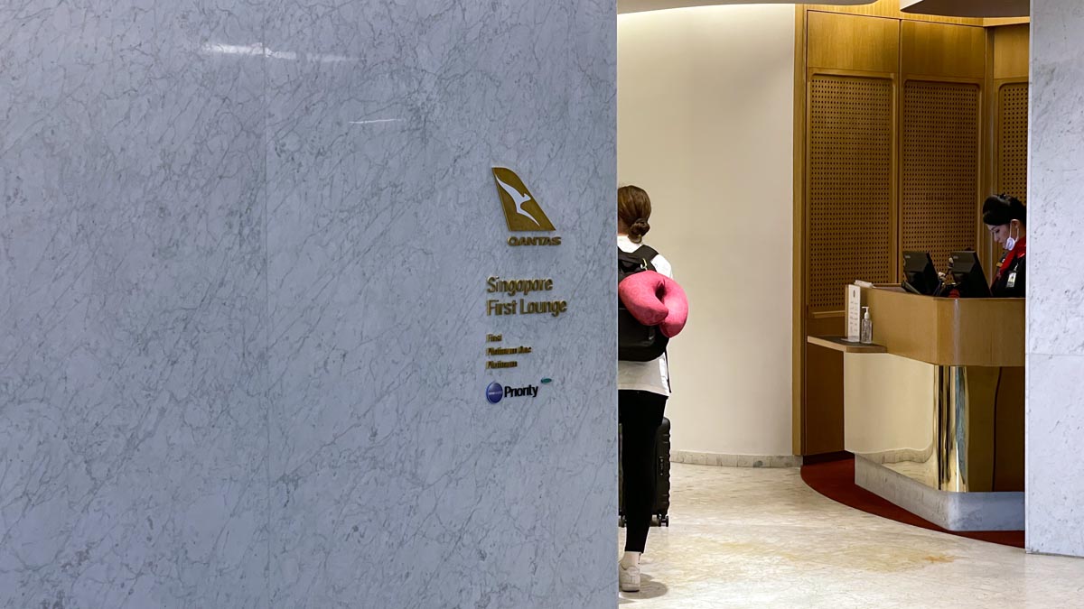 Μια γυναίκα με ροζ μαξιλάρι στην πλάτη της στέκεται σε ένα λόμπι
