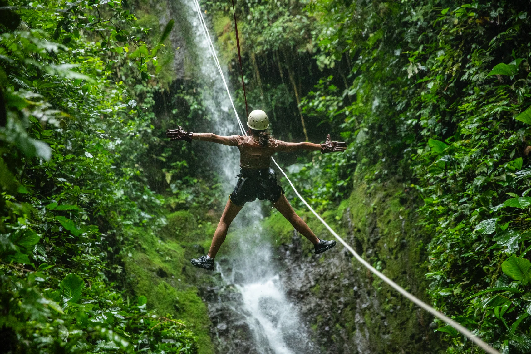 Arenal Volcano, Costa Rica Μια γυναίκα συνδέεται με ένα σχοινί canyoneering σε ένα στενό φαράγγω